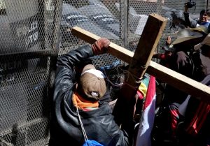 Demonstrators with physical disabilities try to get past a fence during a protest to demand that the government increase their monthly disability subsidy in La Paz