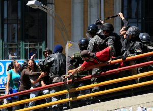 Demonstrators clash with riot police on a pedestrian bridge during a rally protest by people with physical disabilities demanding the government for a monthly subsidy, in La Paz